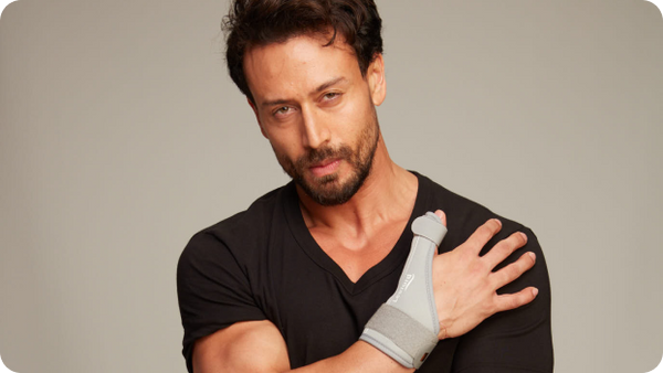 tiger shroff wearing a black shirt and gray thumb spica splint