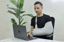 person wear arm pouch in this left arm and working on his laptop