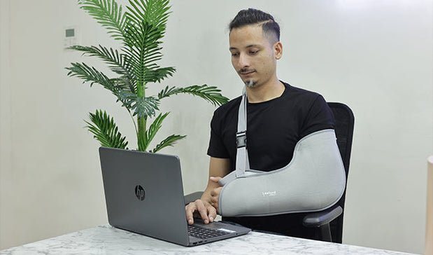 person wear arm pouch in this left arm and working on his laptop