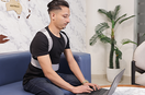 a person wear a posture corrector belt while working on the laptop
