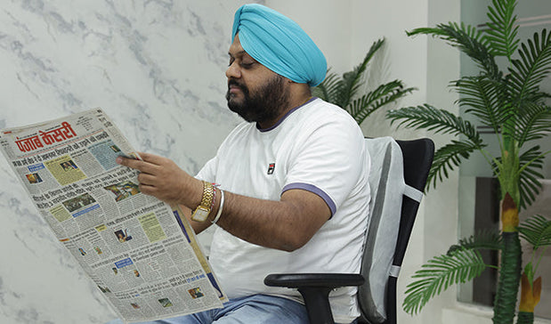 person reading newspaper sitting on a chair with back support