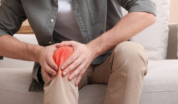 man suffering with knee pain holding his knee