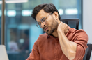 Man suffering with Neck Pain while working on the Laptop desk