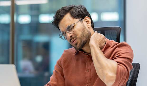 Man suffering with Neck Pain while working on the Laptop desk