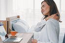 woman hold her back shoulder and showing pain while working on her desk