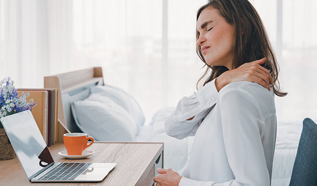 woman hold her back shoulder and showing pain while working on her desk