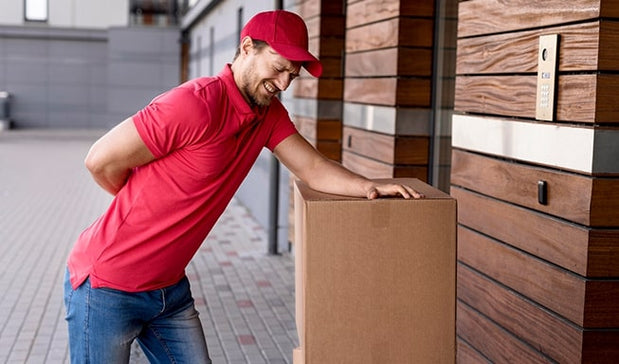 man suffering with back pain while lifting package at work