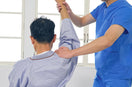 physiotherapist helps the patient in shoulder recovery by exercise