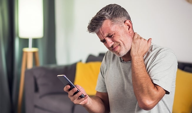 man using amrtphone and suffers from text neck syndrome